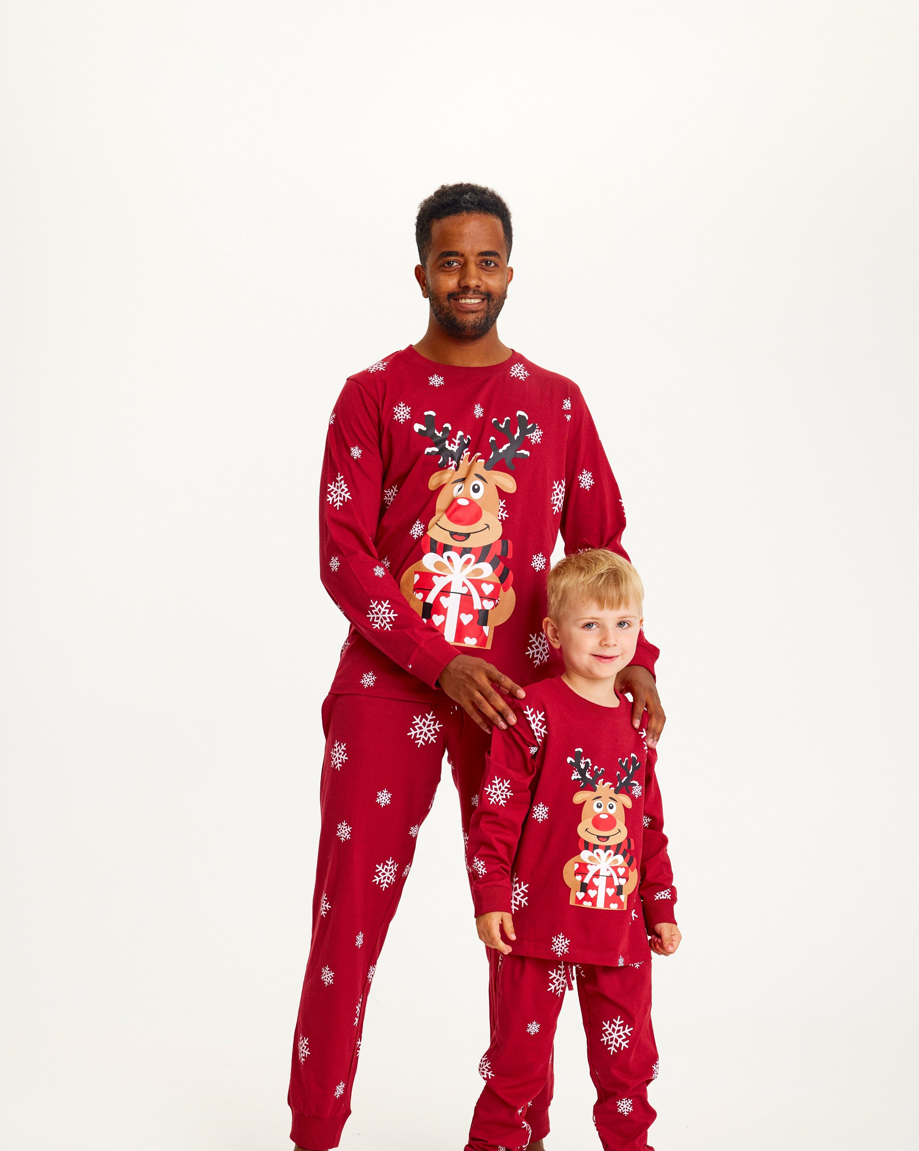 En mand og et barn iført samme julepyjamas.